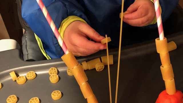 toddler hand close up pasta threading activity