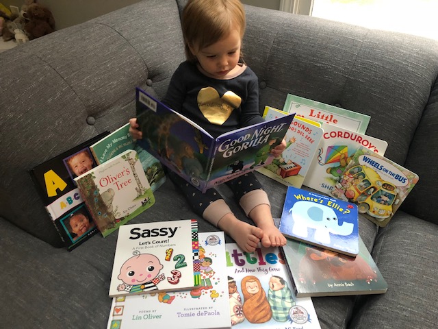 Toddler surrounded by free books from literacy program