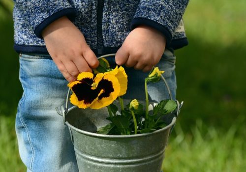 picture of child holding bucket of flowers as a spring speech therapy theme
